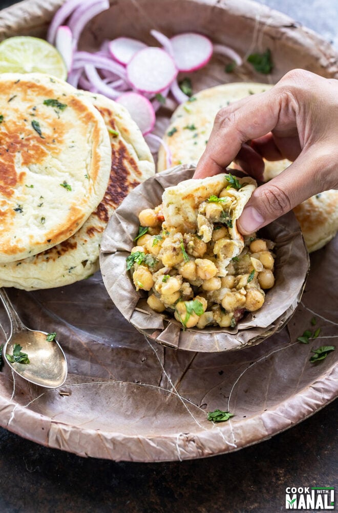 a kulcha being dipped into matar chaat