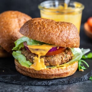 burger with a patty, with a yellow sauce drizzled between the buns and lettuce placed on the bottom of the burger