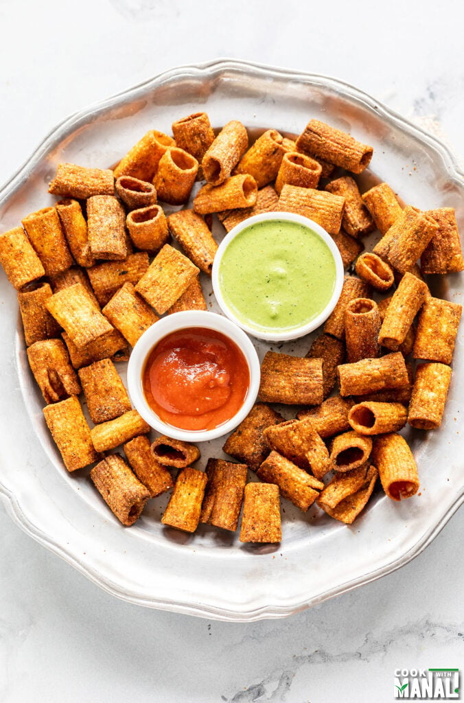 spiced pasta arranged on a plate with 2 dipping sauces- chutney and ketchup