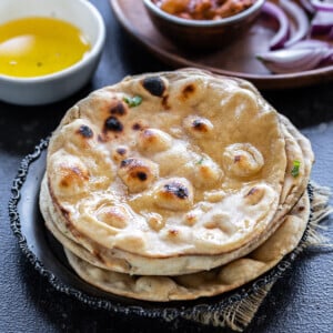 stack on rotis with bowl of ghee and bowl of curry in the background