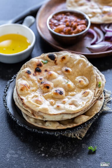 stack on rotis with bowl of ghee and bowl of curry in the background