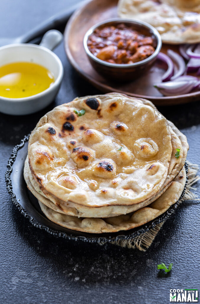 stack on rotis with bowl of ghee and bowl of curry in the background