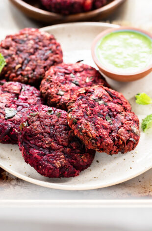 beetroot tikkis arranged on a plate with bowl of chutney on the side