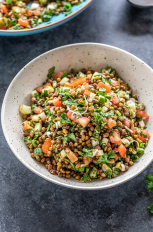 bowl of lentil salad garnished with mint and parsley