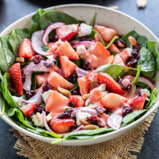 bowl of salad with spinach strawberries, almonds