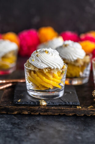 badam halwa served in glass jars topped with whipped cream and garlands of flowers placed in the background