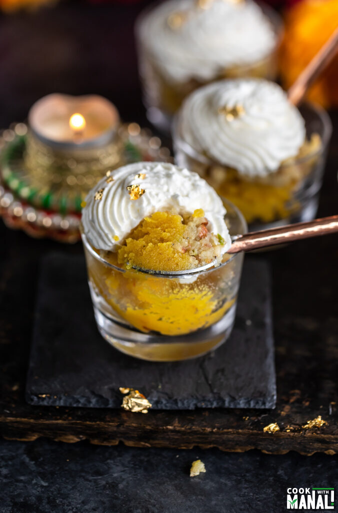 spoon scooping out badam halwa from a glass jar to show the texture of the halwa