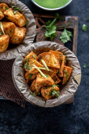 crispy fried potatoes served in a bowl and garnished with ginger juliennes and cilantro