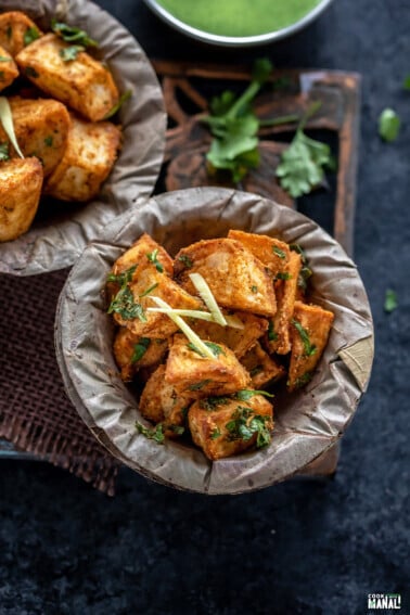 crispy fried potatoes served in a bowl and garnished with ginger juliennes and cilantro