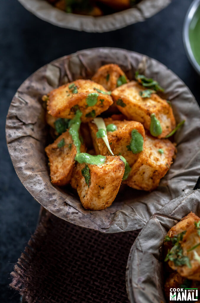crispy fried potatoes served in a bowl and garnished with ginger juliennes and cilantro and chutney
