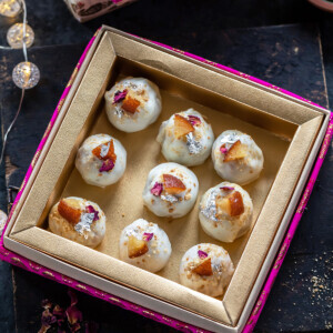 9 pieces of truffles coated with white chocolate placed in a pink color mithai box