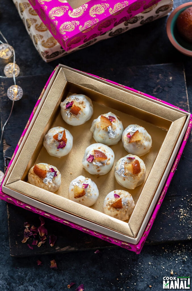 9 pieces of truffles coated with white chocolate placed in a pink color mithai box