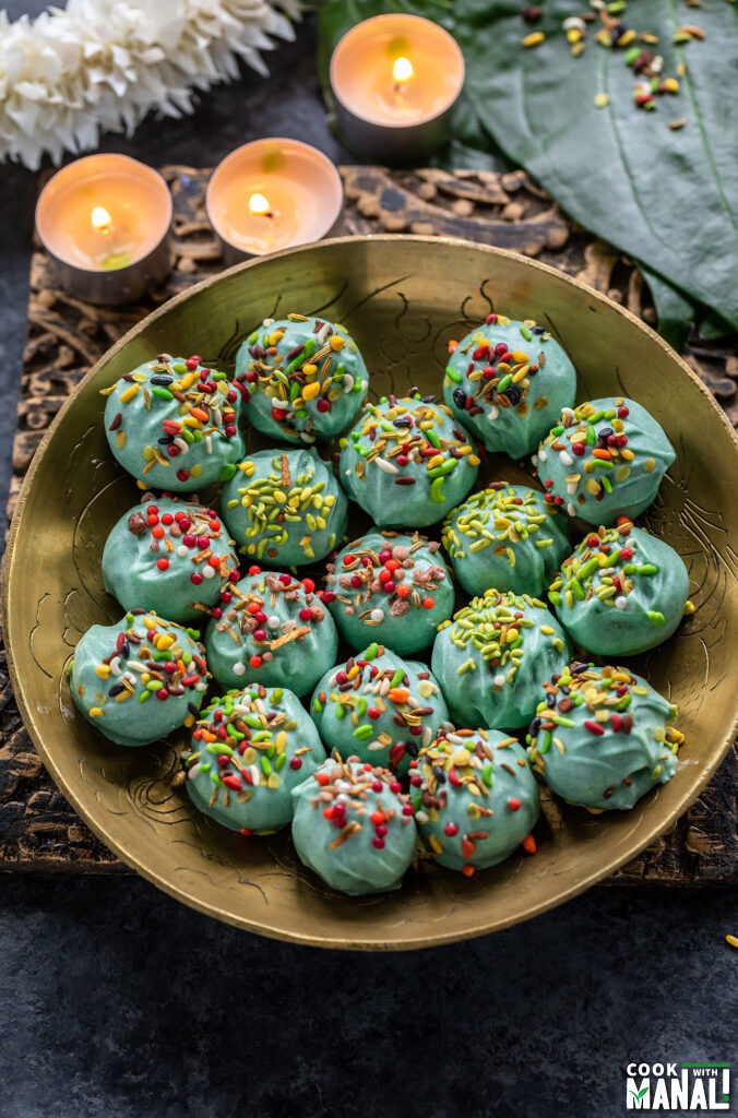 green color truffles placed in a gold plate with 3 tealights placed in the back