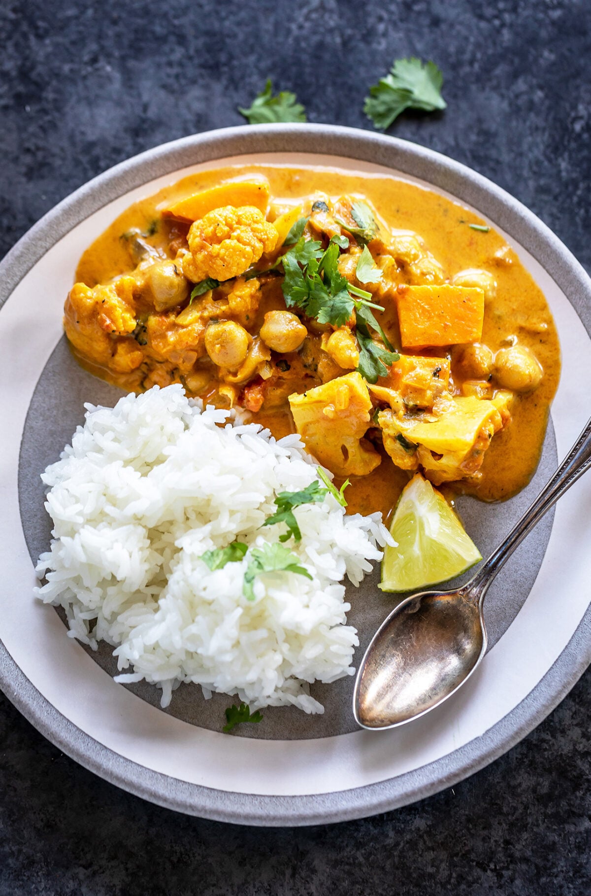 vegetable curry garnished with cilantro served with rice and a lime wedge