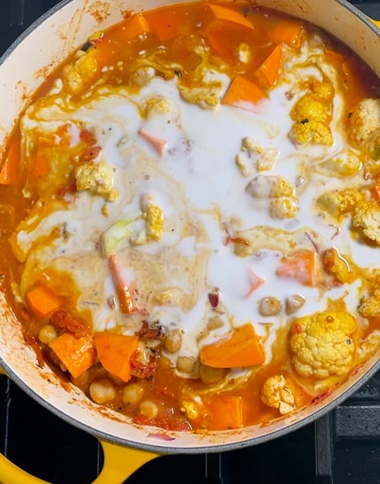 coconut milk added to a big pot of curry