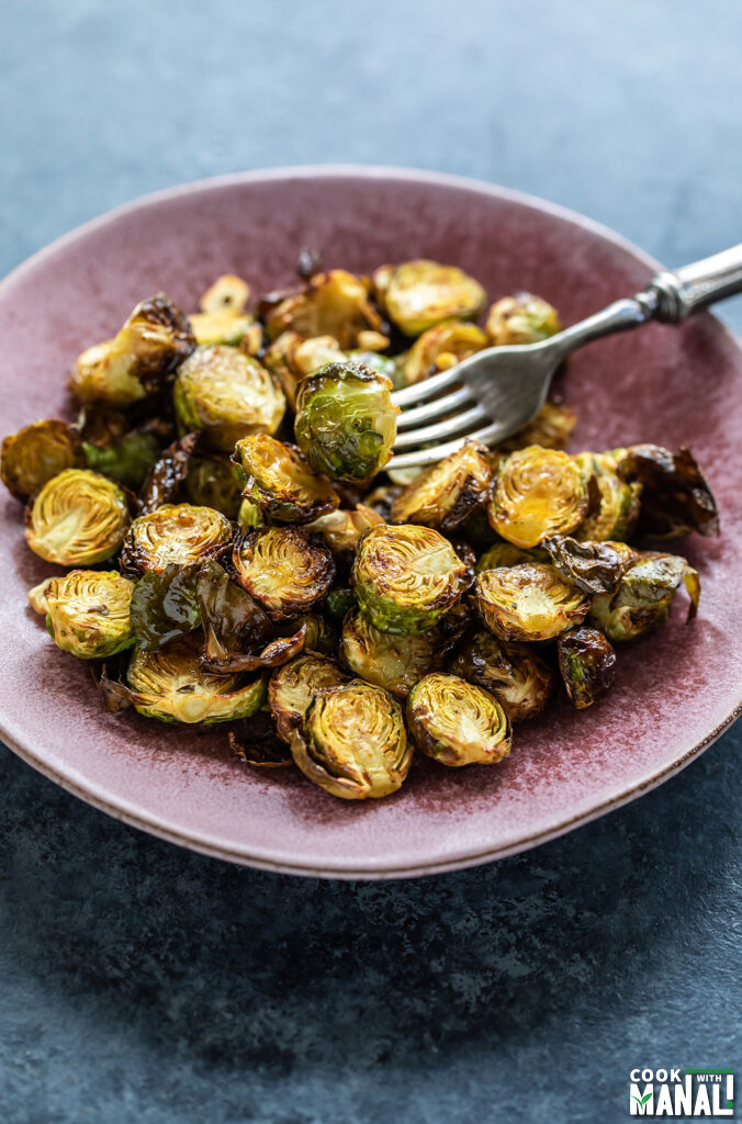 a fork picking up a roasted Brussel sprout from a plate