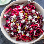 diced beets with sliced onions and goat cheese served in a white bowl