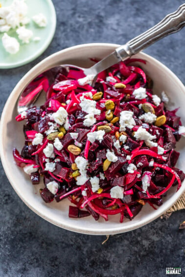 diced beets with sliced onions and goat cheese served in a white bowl