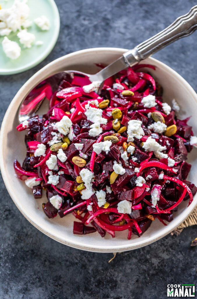 diced beets with sliced onions and goat cheese served in a white bowl