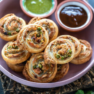 puff pastry pinwheels arranged on a plate and served with chutneys