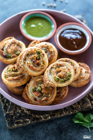 puff pastry pinwheels arranged on a plate and served with chutneys