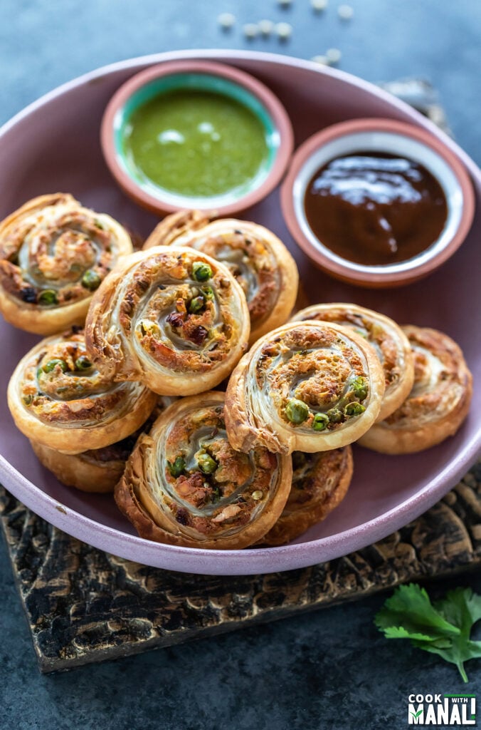 puff pastry pinwheels arranged on a plate and served with chutneys