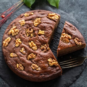 a slice of date walnut cake cut from the cake and placed on a serving board