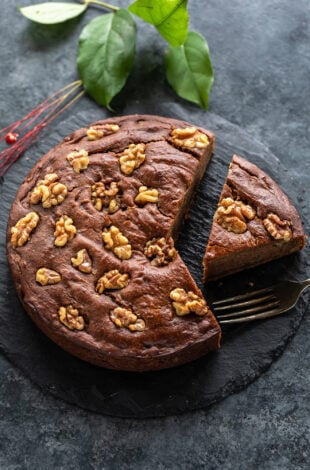 a slice of date walnut cake cut from the cake and placed on a serving board