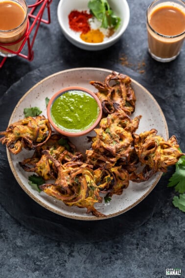 onion pakoda in a plate with a bowl of cilantro chutney