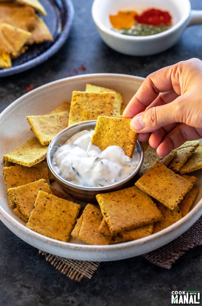 hand dipping a cracker into a dip 