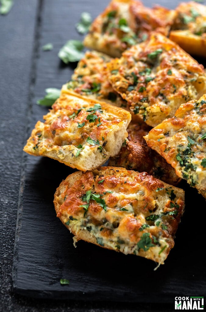 cheesy garlic bread slices placed on a black serving board