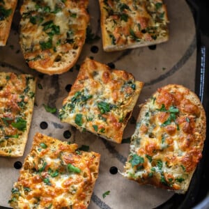 seven pieces of garlic bread arranged in an air fryer