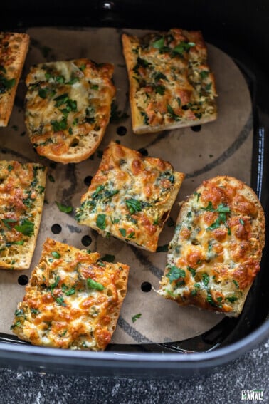 seven pieces of garlic bread arranged in an air fryer