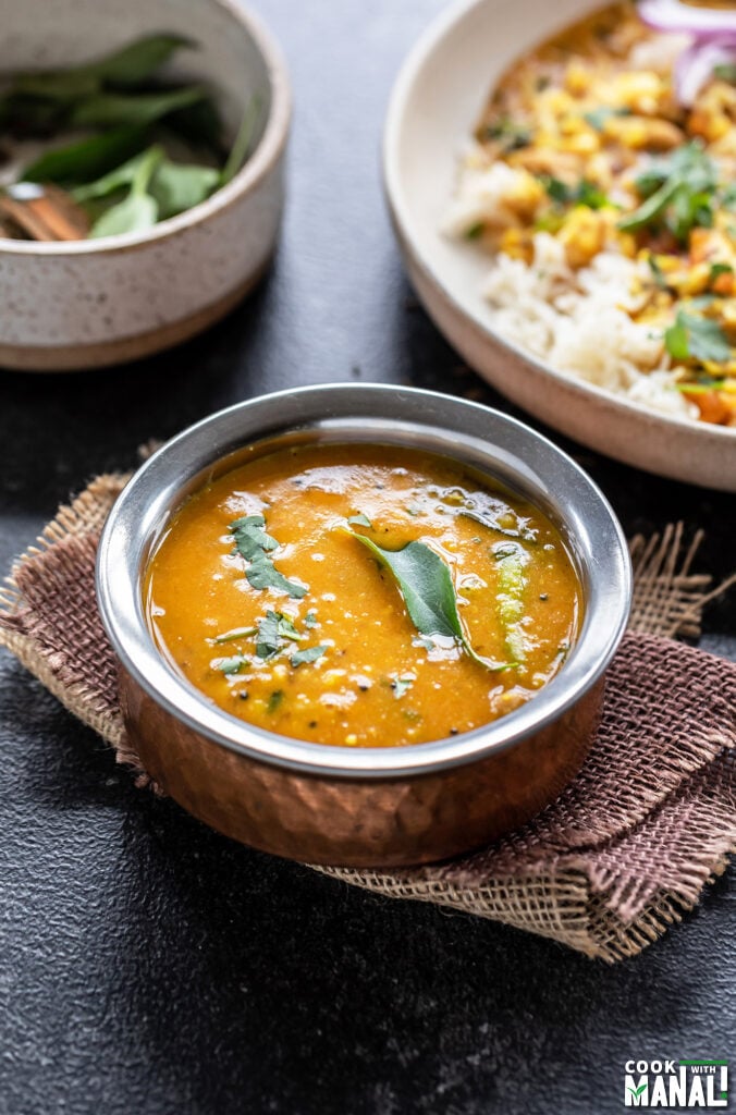 dal in a copper bowl garnished with curry leaves and cilantro