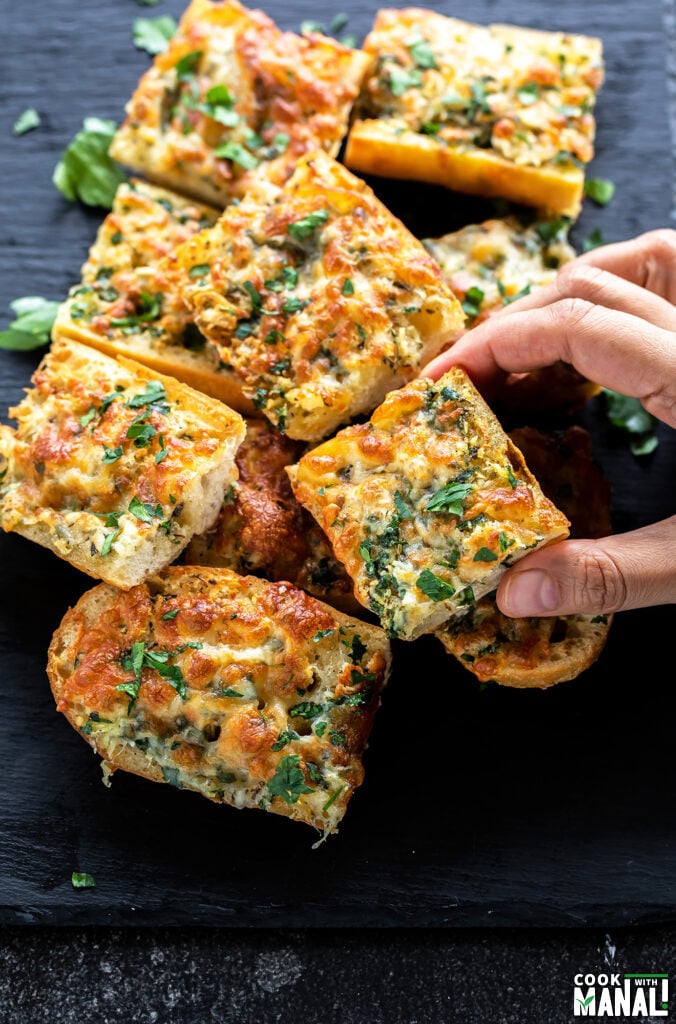 hands holding a slice of garlic bread