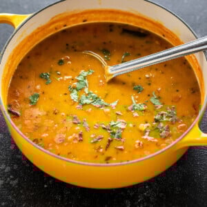 dal in a yellow color pot with ladle and garnished with cilantro