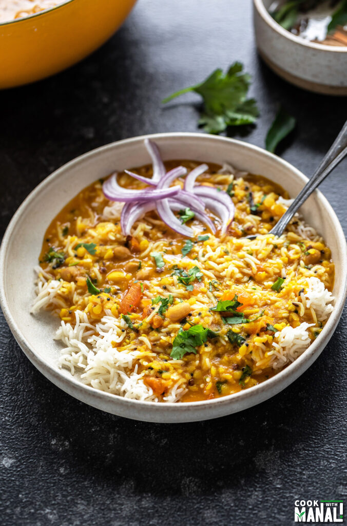 rice and dal served in a white bowl with sliced onions