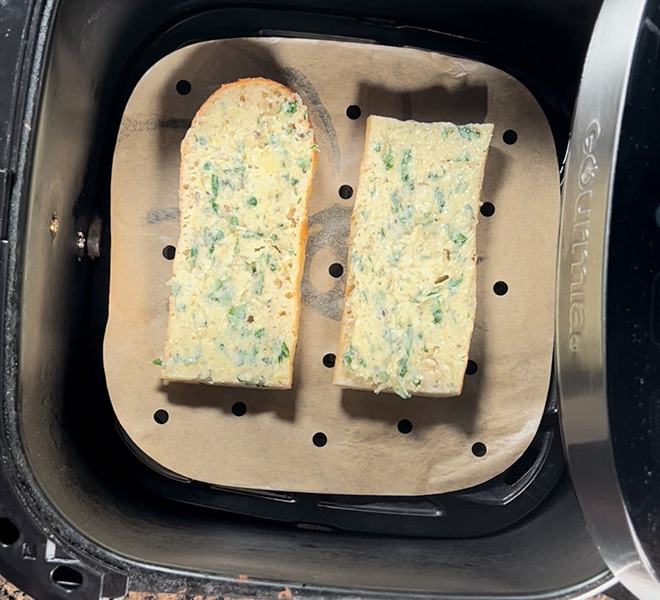 2 pieces of bread with butter spread on top placed in the air fryer