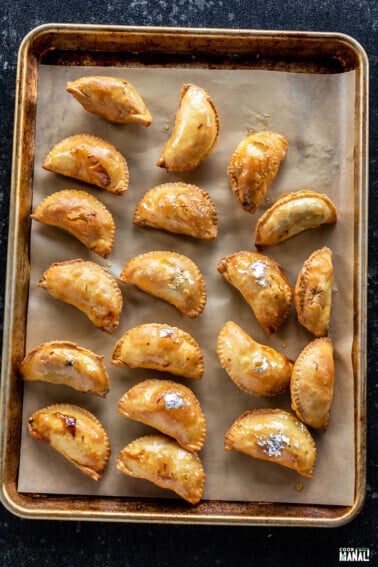 gujiyas arranged on a baking tray