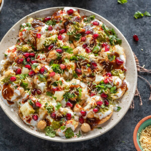 plate of papdi chaat garnished with cilantro, pomegranate, sev