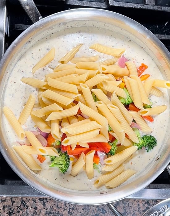 penne pasta and vegetables added to white sauce