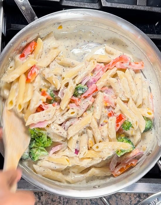 penne pasta with vegetables in a white sauce in a steel pan