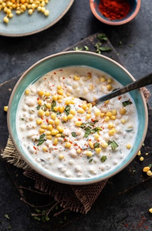 yogurt in a blue bowl topped with boondi and chopped mint