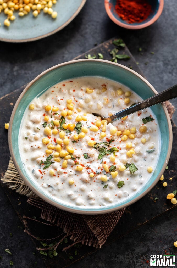 yogurt in a blue bowl topped with boondi and chopped mint