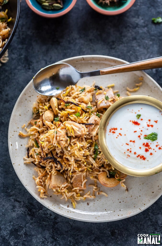 jackfruit biryani served on a plate with a bowl of raita