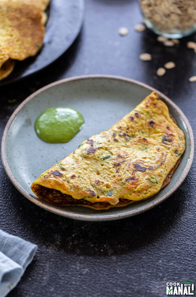 a chilla (savory pancake) served in a plate with cilantro chutney