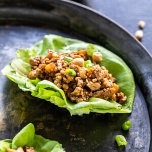 tofu lettuce wrap topped with green onions with bowls of sauce in the background