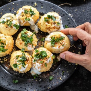 golgappa topped with cilantro and sev arranged on a plate