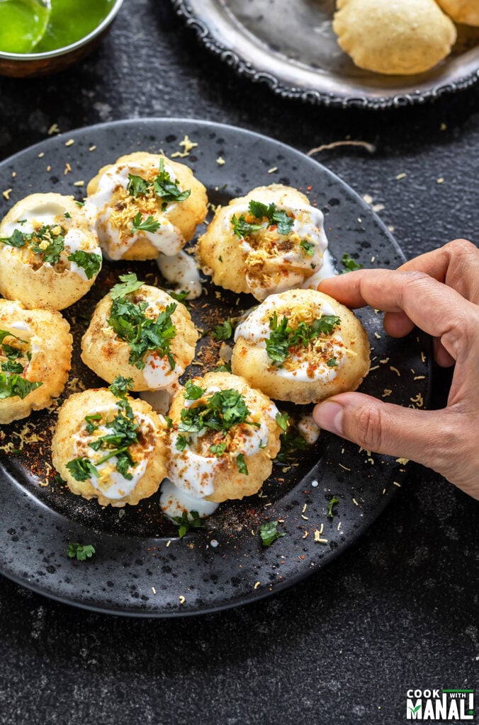 golgappa topped with cilantro and sev arranged on a plate