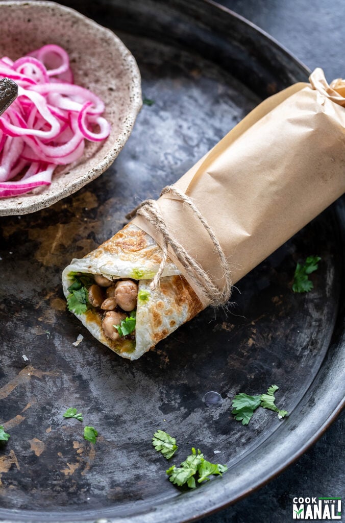 a kathi roll wrapped in parchment paper and tied with a thread